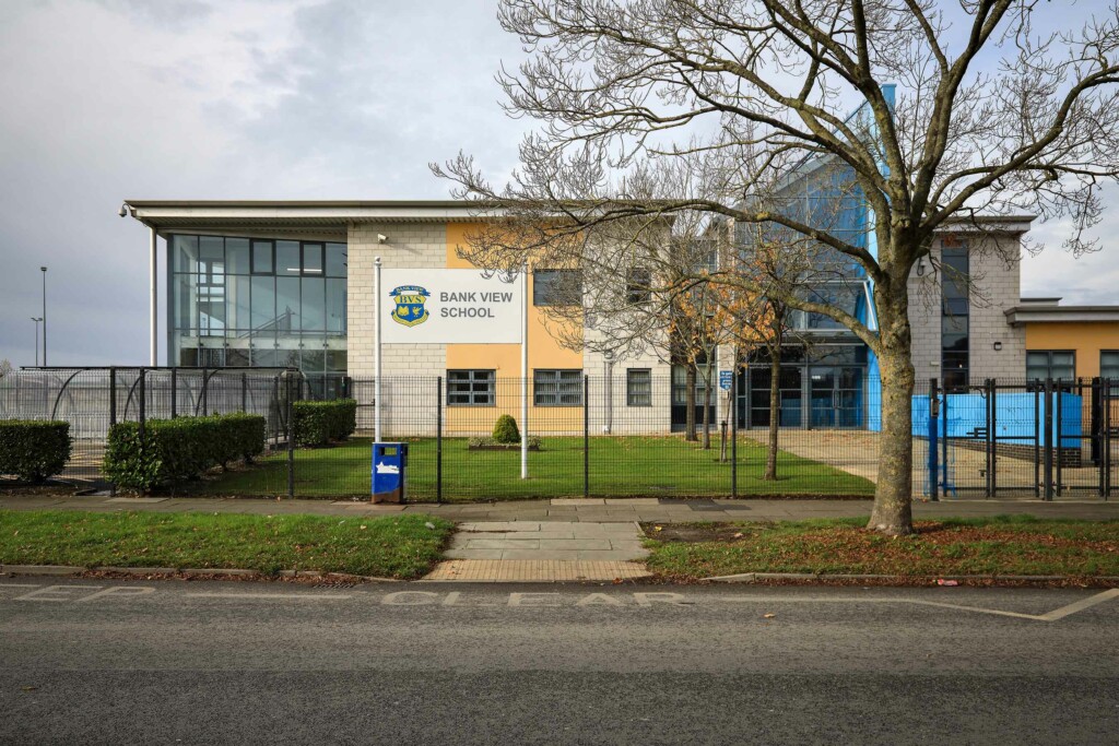 Image of a school with fence and grass in foreground